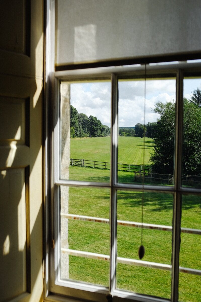 a window with a view of a field and trees